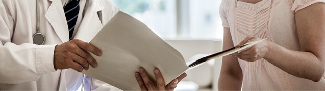 An image of a doctor showing a patient a white folder that contains patient information