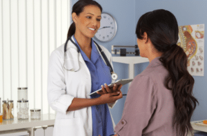 African American gynecologist talking to patient with tablet
